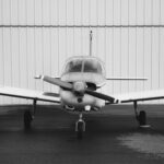 Front view of a single-engine general aviation airplane parked outside a hangar