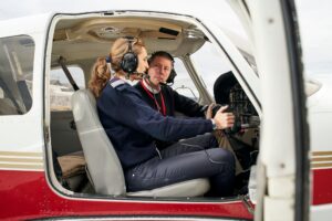 Flight instructor teaching a student pilot inside a small training aircraft cockpit