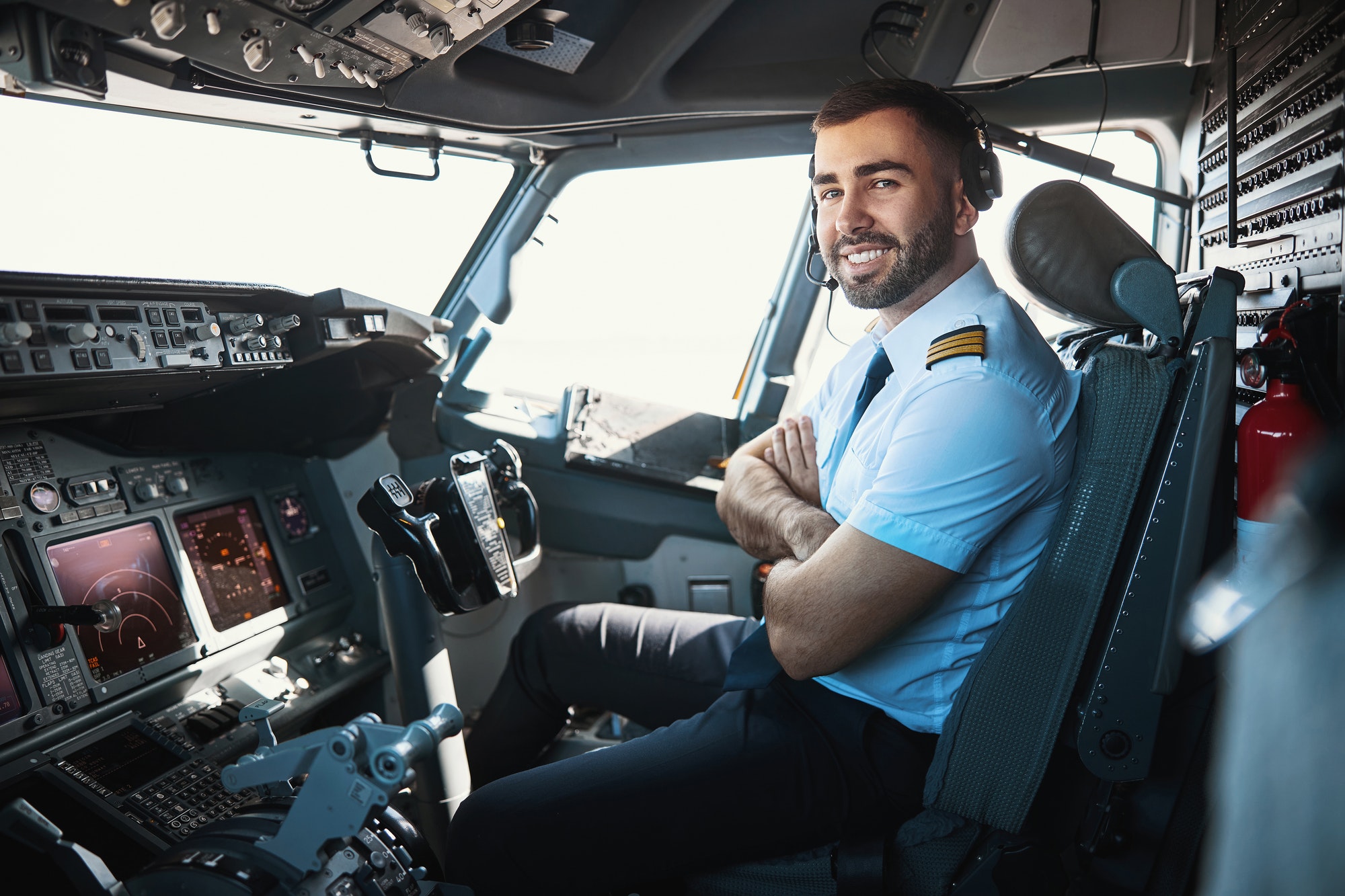 Airline pilot sitting in the cockpit, wearing a headset and uniform, preparing for flight