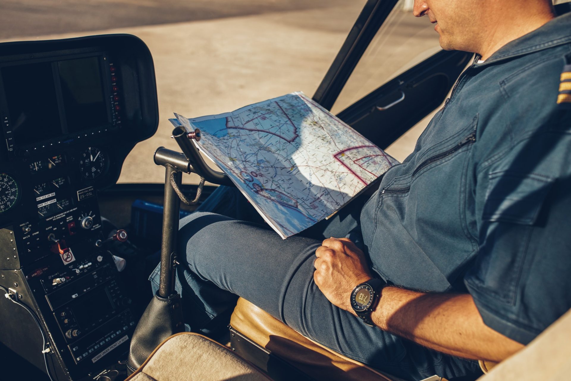 Pilot trainee reviewing a sectional navigation chart inside a cockpit while preparing for private pilot license training