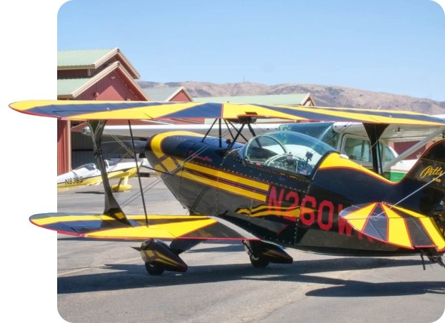 Yellow biplane performing an aerobatic maneuver above Los Angeles